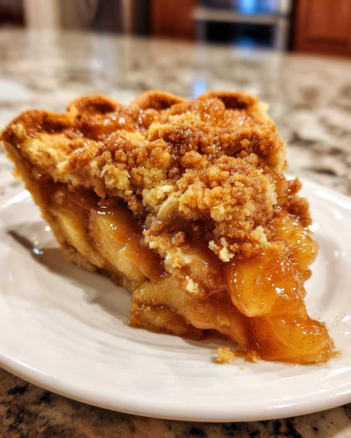 Close-up of a slice of apple pie dump cake on a white plate, showing the apple filling and crumb topping.