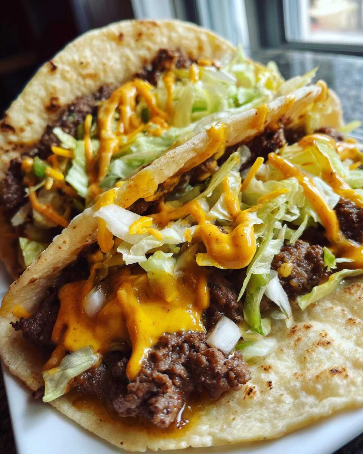 Close-up of two Big Mac tacos filled with seasoned ground beef, shredded lettuce, cheese, and special sauce.