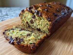 Close-up of a sliced loaf of chocolate chip zucchini bread on a wooden cutting board.