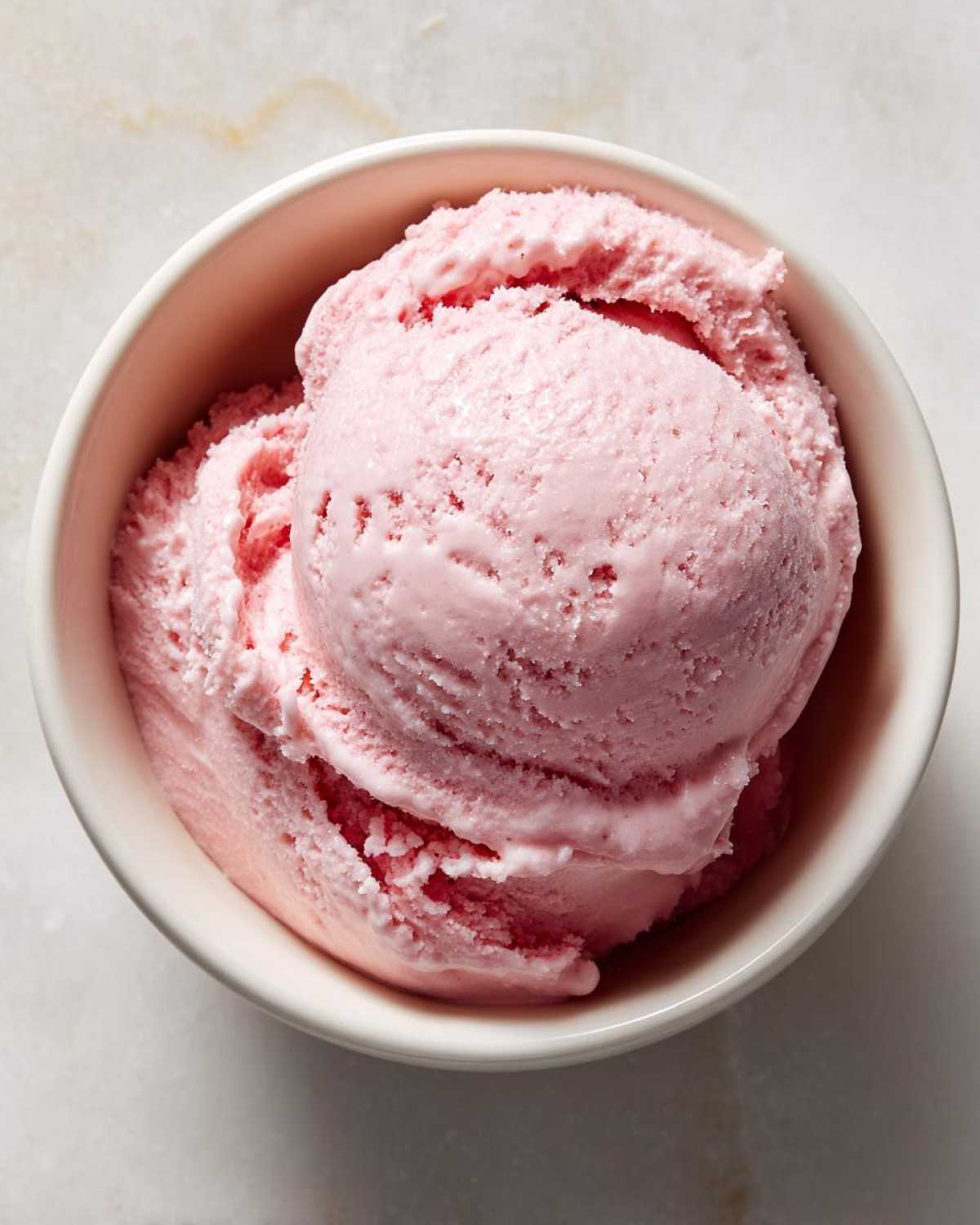 Overhead shot of a bowl filled with scoops of creamy pink cottage cheese ice cream.