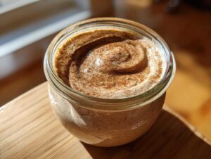 Close-up of creamy blended overnight oats in a glass jar, topped with a swirl of cinnamon powder.
