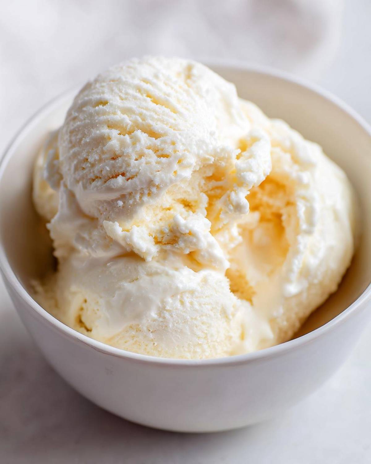 Close-up of a white bowl filled with scoops of creamy high protein cottage cheese ice cream.
