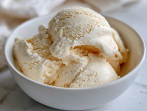 Close-up of a white bowl filled with scoops of creamy high protein cottage cheese ice cream.