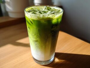 Close-up of a tall glass filled with a vibrant green iced matcha latte, showing layers of milk and matcha.