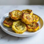 A white plate filled with golden-brown, roasted patty pan squash, seasoned with herbs and garlic.