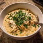 A bowl of creamy white chicken chili topped with fresh cilantro and cheese.