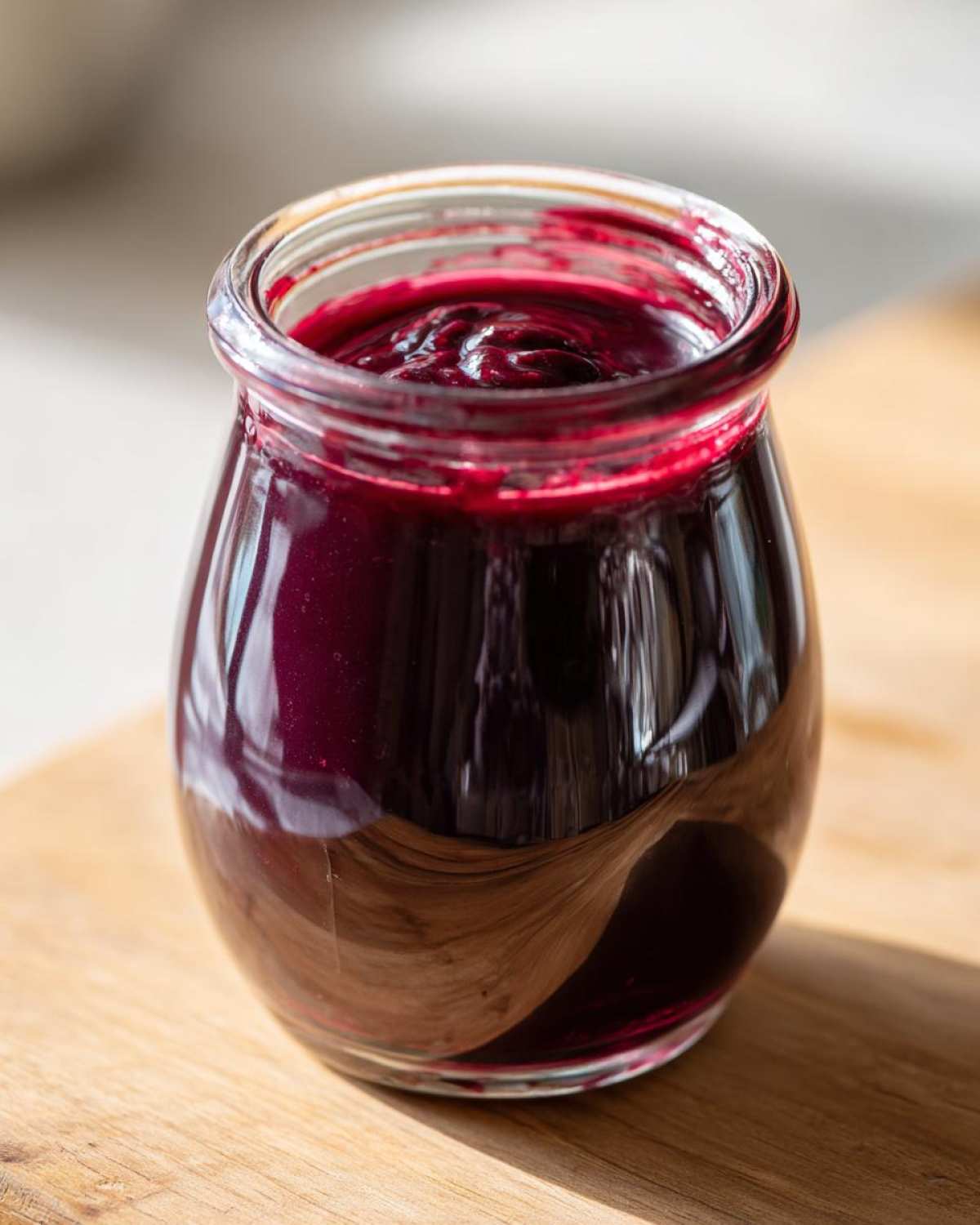 A jar filled with homemade elderberry syrup recipe, showcasing its rich, dark color and thick consistency.