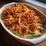 Overhead view of a freshly baked green bean casserole in a white dish, topped with crispy fried onions.