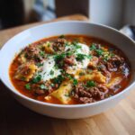 A bowl of lasagna soup, featuring pasta, beef, tomato broth, ricotta cheese, and parsley.