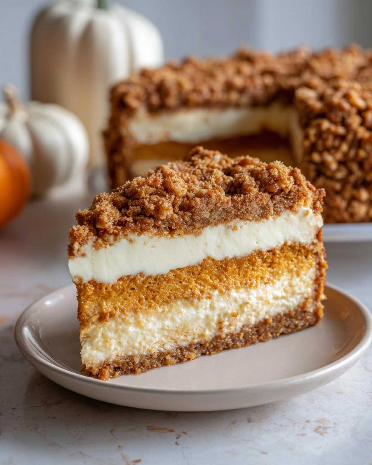A delicious slice of pumpkin crunch cake with layers of pumpkin and cream cheese filling, topped with a crunchy crumble.