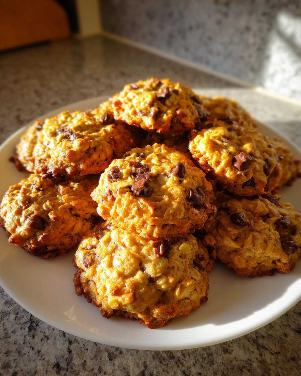 A stack of pumpkin oatmeal cookies with chocolate chips on a white plate, ready to eat.