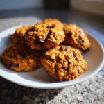 A plate of freshly baked pumpkin oatmeal cookies with chocolate chips, perfect for breakfast or a snack.