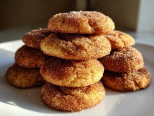 A stack of soft apple cider cookies coated in cinnamon sugar on a white plate.