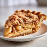 A delicious slice of apple crumble pie with a golden crust and sweet crumble topping.