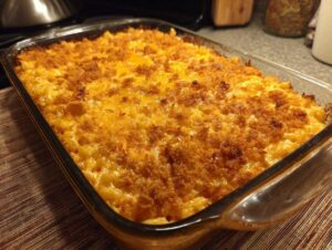 A close-up of a freshly baked cheesy hashbrown casserole in a glass baking dish, with a golden brown, crunchy topping.