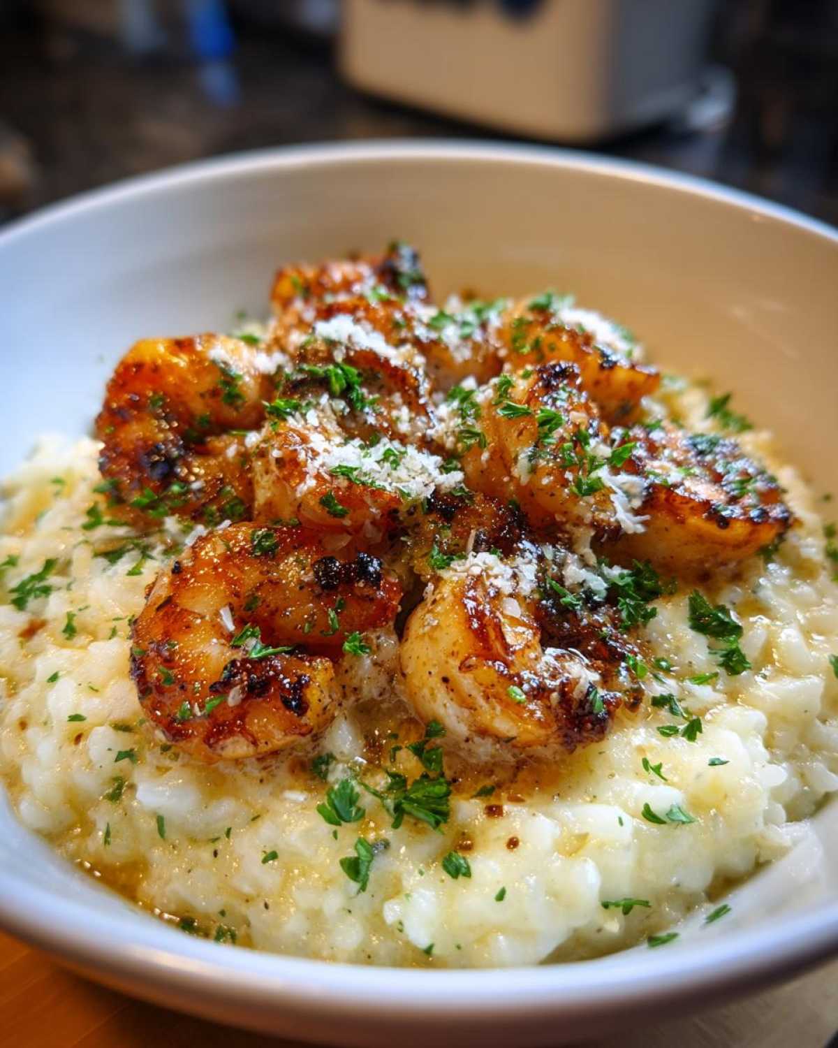 A bowl of creamy garlic parmesan rice topped with seasoned shrimp and fresh parsley.