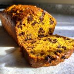 A sliced loaf of chocolate chip pumpkin bread, showcasing its moist texture and rich color.