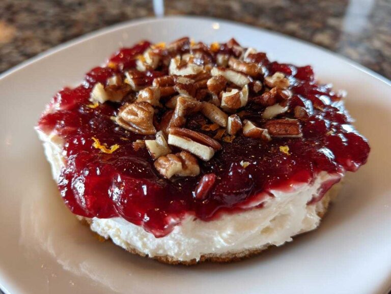 Close-up of a slice of cranberry cream cheese dip topped with cranberry sauce and chopped pecans.