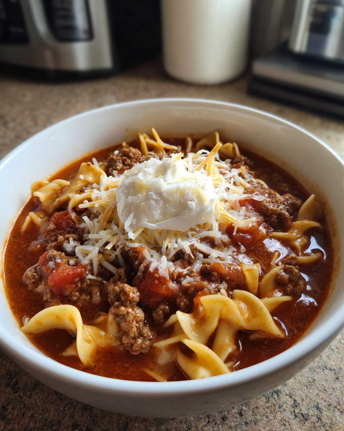 A bowl of crockpot lasagna soup topped with ricotta cheese and shredded cheese.
