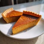 Two slices of moist and flavorful crustless pumpkin pie on a white plate, ready to be enjoyed.