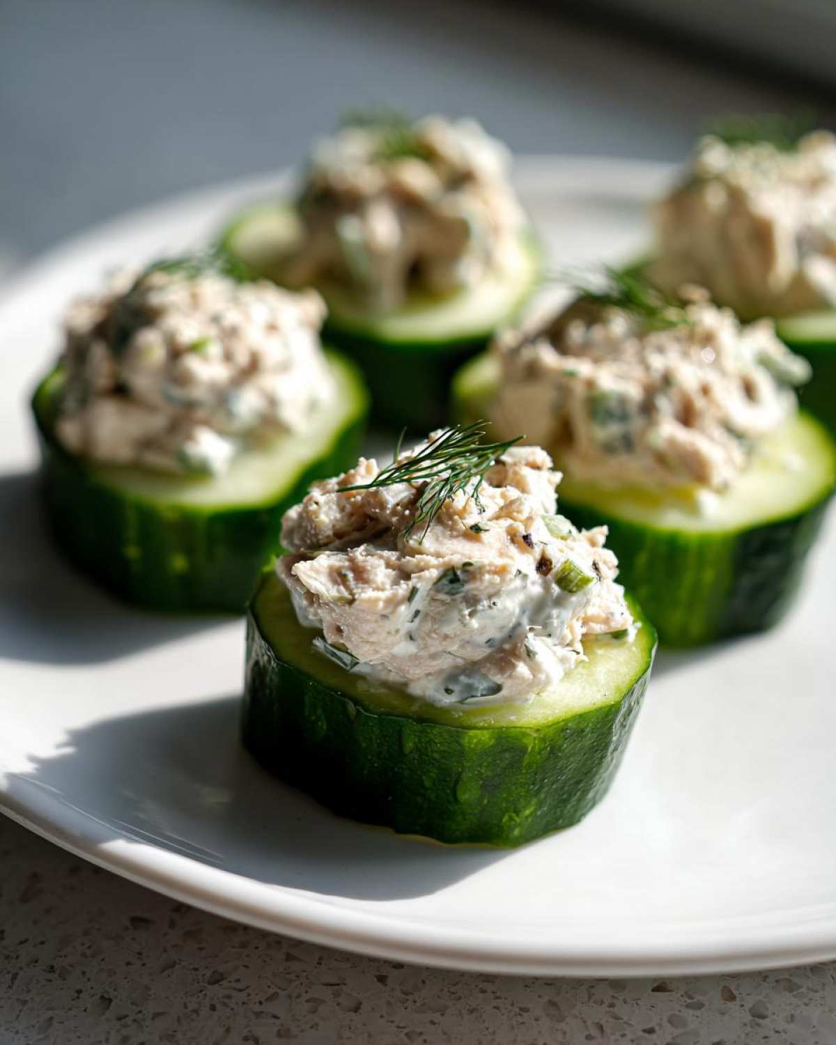 Cucumber tuna salad appetizers on a white plate, garnished with dill. Ready to eat!