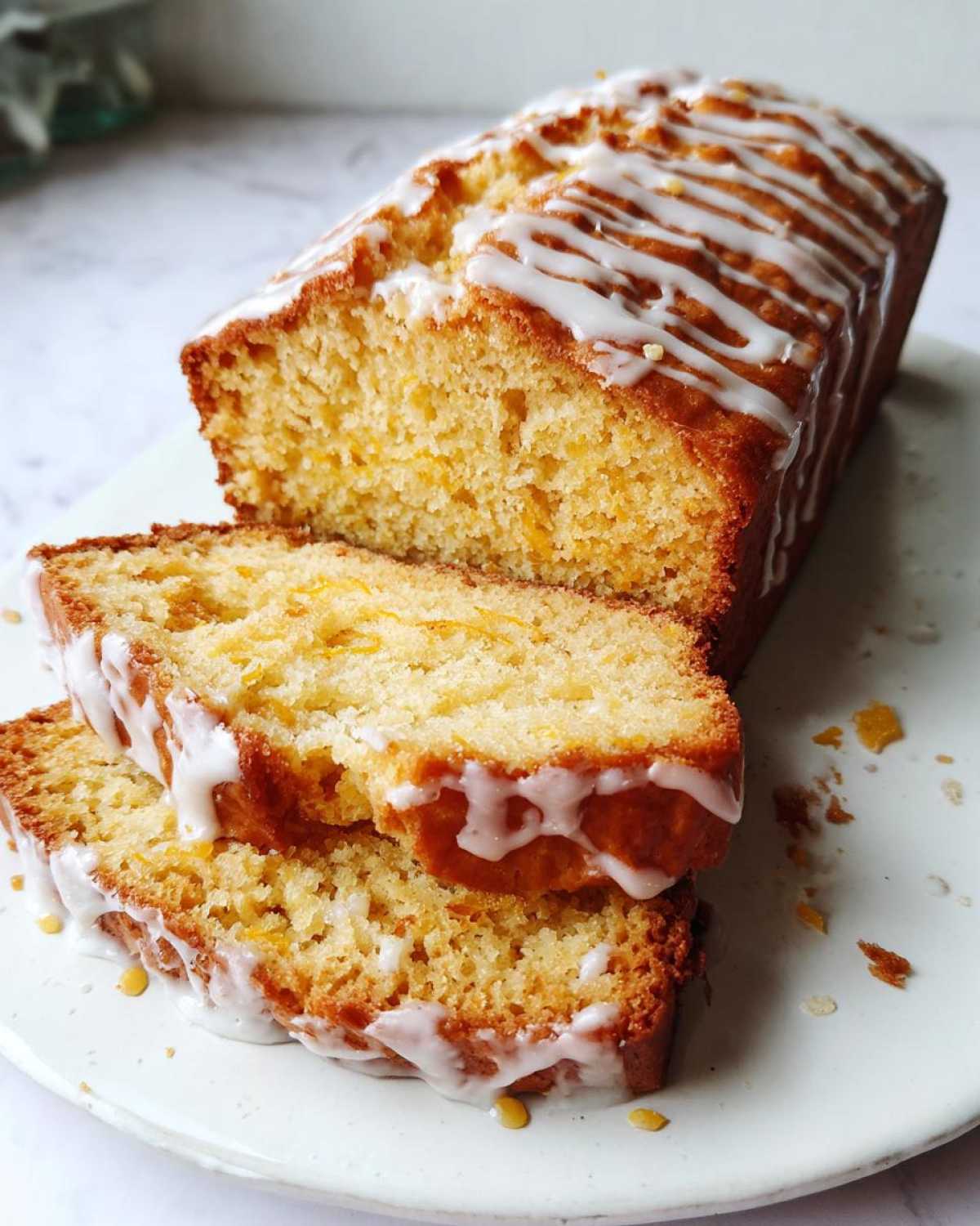 Close-up of two slices of moist eggnog bread, drizzled with a sweet white glaze.