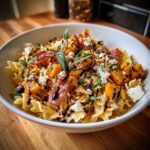 Bowl of fall pasta salad with roasted squash, bacon, cheese, sage, and balsamic glaze.