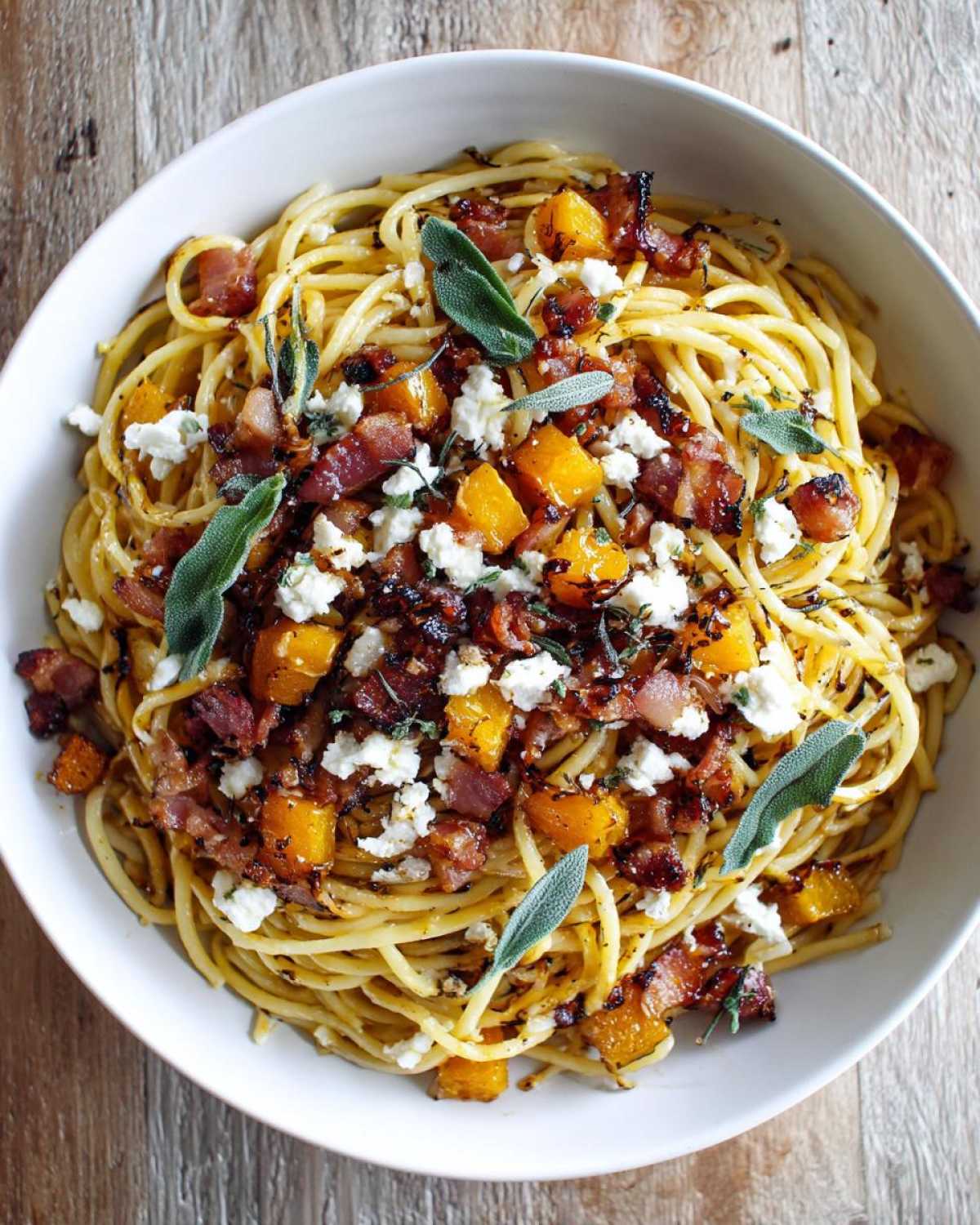 Overhead shot of fall pasta salad with spaghetti, roasted squash, bacon, goat cheese, and sage.