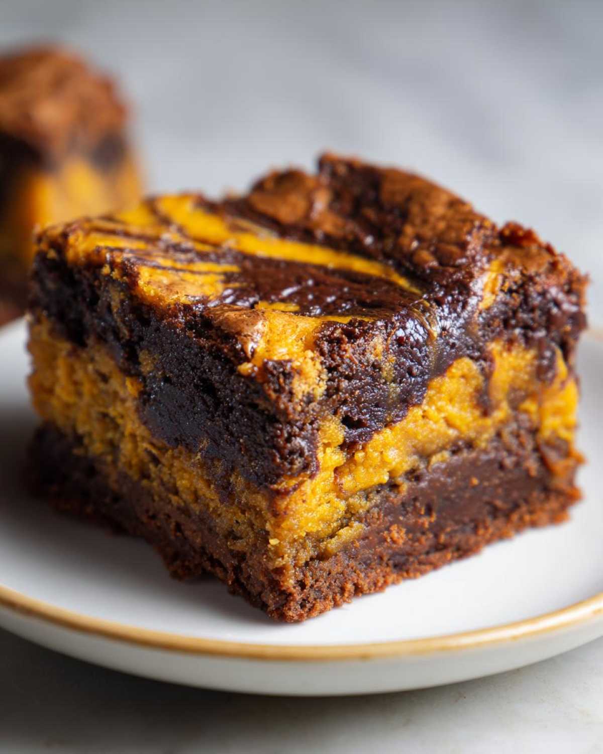 A close-up of a fudgy pumpkin brownie slice with swirls of chocolate and pumpkin batter.