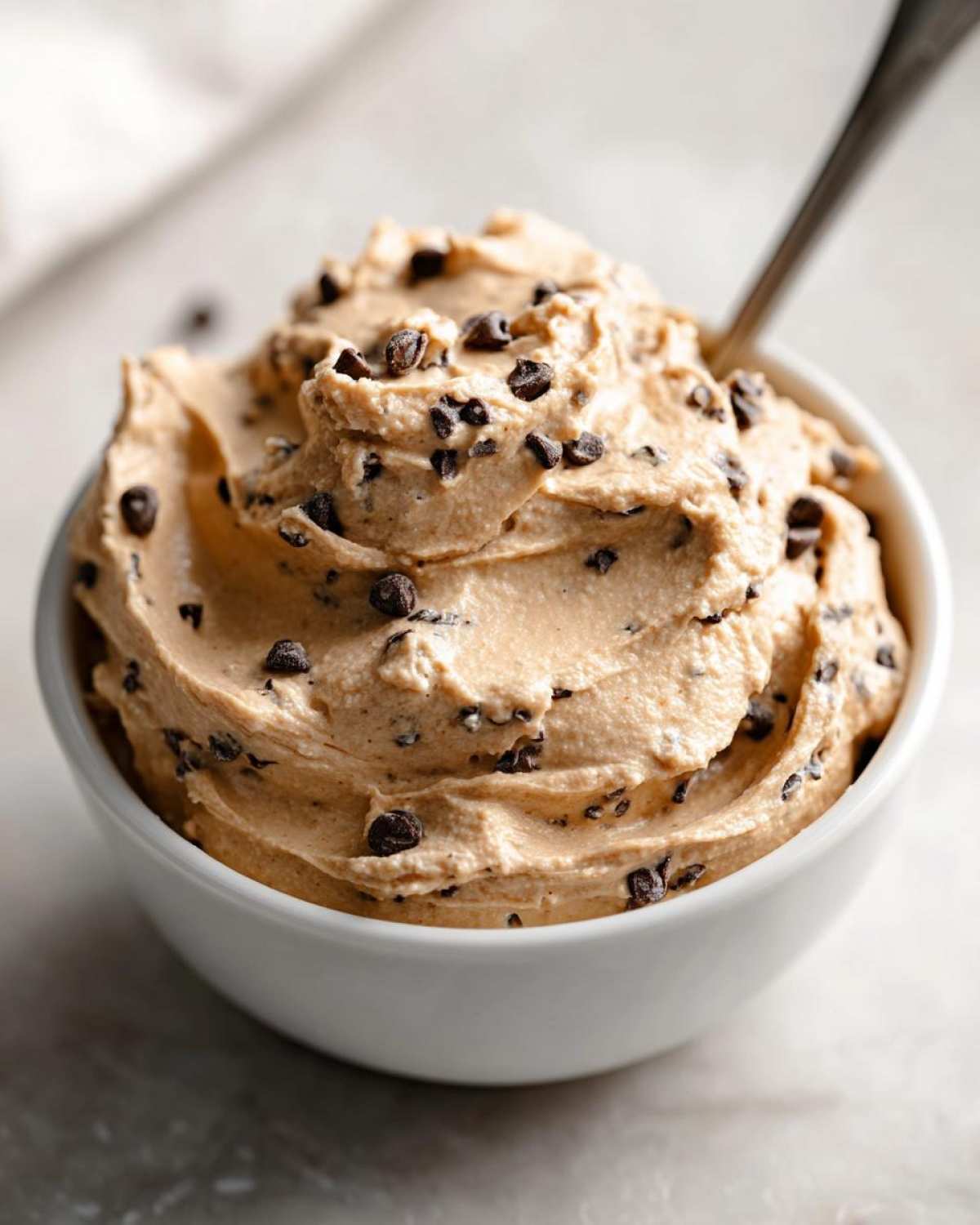 A bowl of creamy high protein cookie dough dip with chocolate chips, ready to be enjoyed with a spoon.