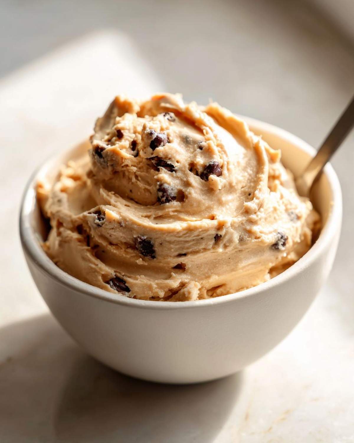 A bowl of creamy high protein cookie dough dip with chocolate chips, ready to be enjoyed with a spoon.