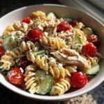 Bowl of high protein pasta salad with tuna, tomatoes, cucumbers, and feta cheese.