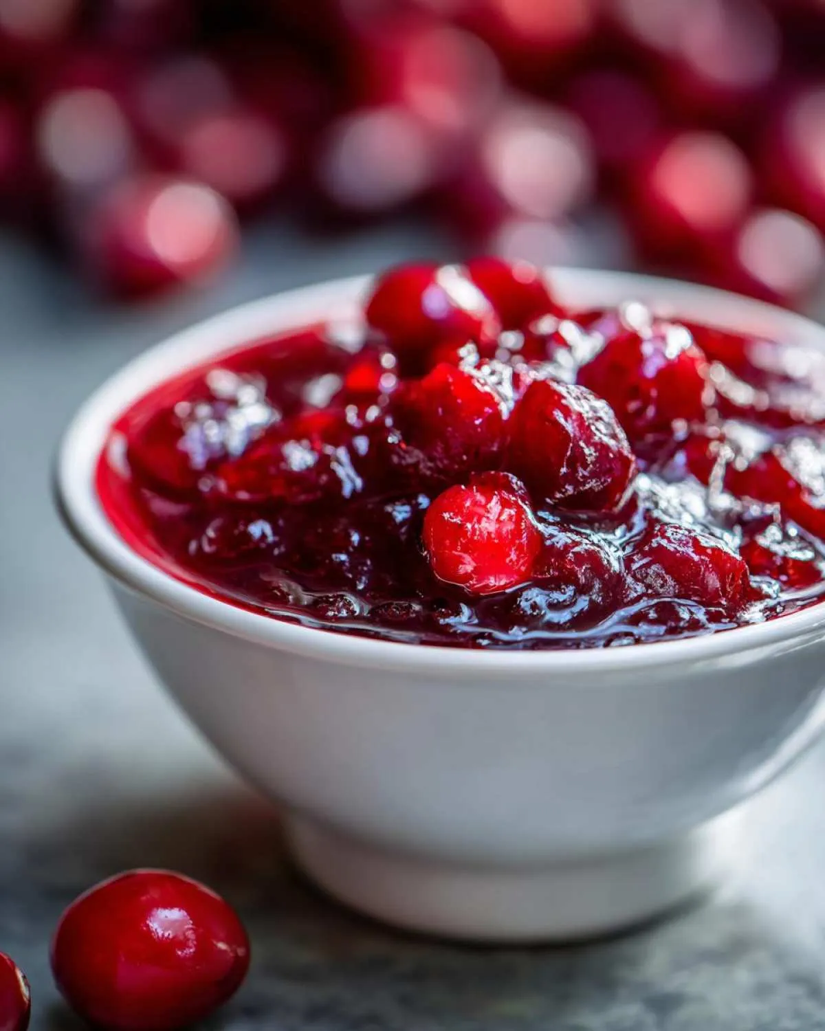 Close-up of delicious homemade cranberry sauce in a white bowl, with whole cranberries visible.
