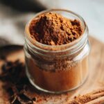 Close-up of homemade pumpkin spice blend in a glass jar with star anise and cinnamon sticks.