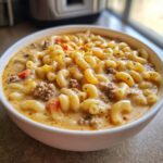 A close-up view of a bowl of macaroni cheeseburger soup, filled with elbow macaroni, ground beef, and a creamy cheese sauce.