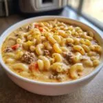 A close-up view of a bowl of macaroni cheeseburger soup, filled with elbow macaroni, ground beef, and a creamy cheese sauce.