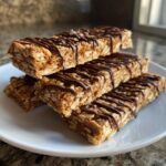 A stack of four protein bars homemade drizzled with chocolate on a white plate.