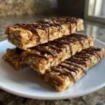 A stack of four protein bars homemade drizzled with chocolate on a white plate.