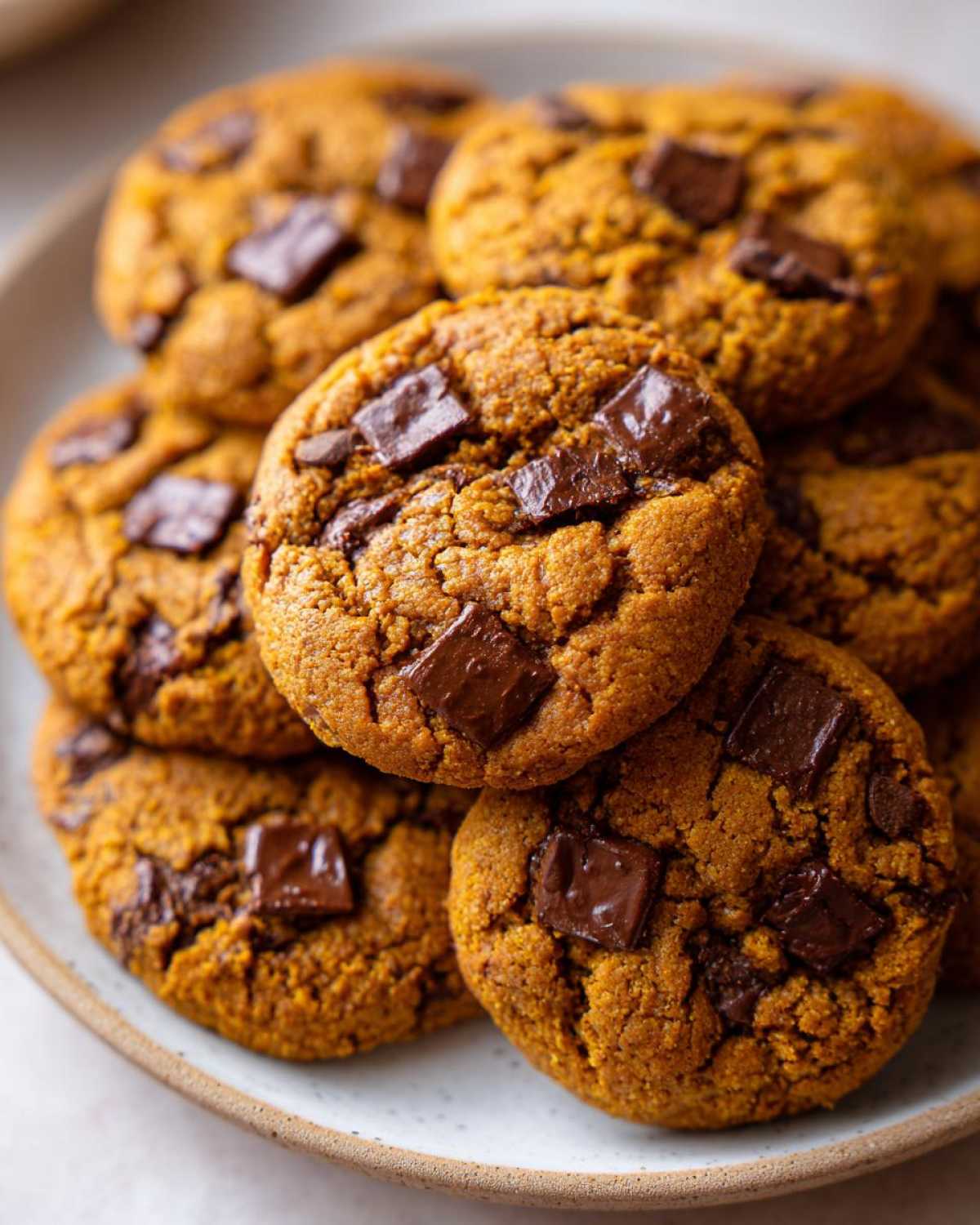 A stack of delicious pumpkin chocolate chip cookies on a plate, ready to be enjoyed.