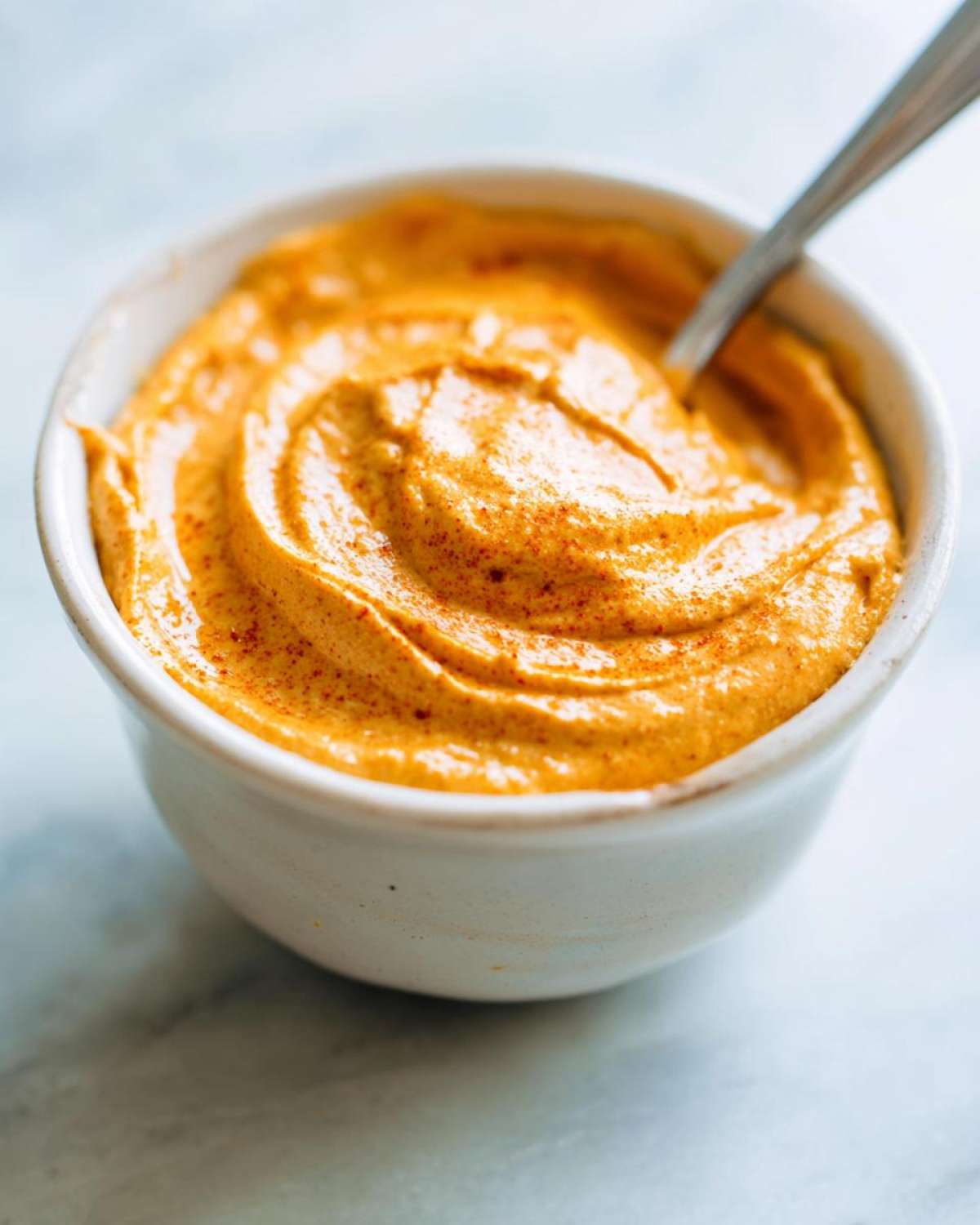 Close-up of pumpkin cream cheese in a bowl with a spoon, showing its smooth texture and spiced appearance.