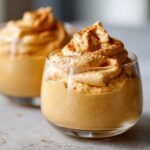 Close-up of a glass filled with creamy pumpkin mousse, topped with cinnamon.