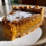 A single slice of pumpkin pie bars dusted with powdered sugar on a white plate.