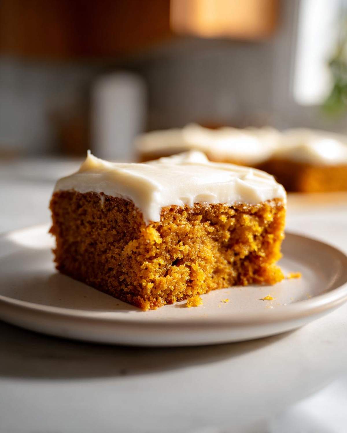 A slice of moist pumpkin sheet cake topped with creamy frosting, ready to be enjoyed.