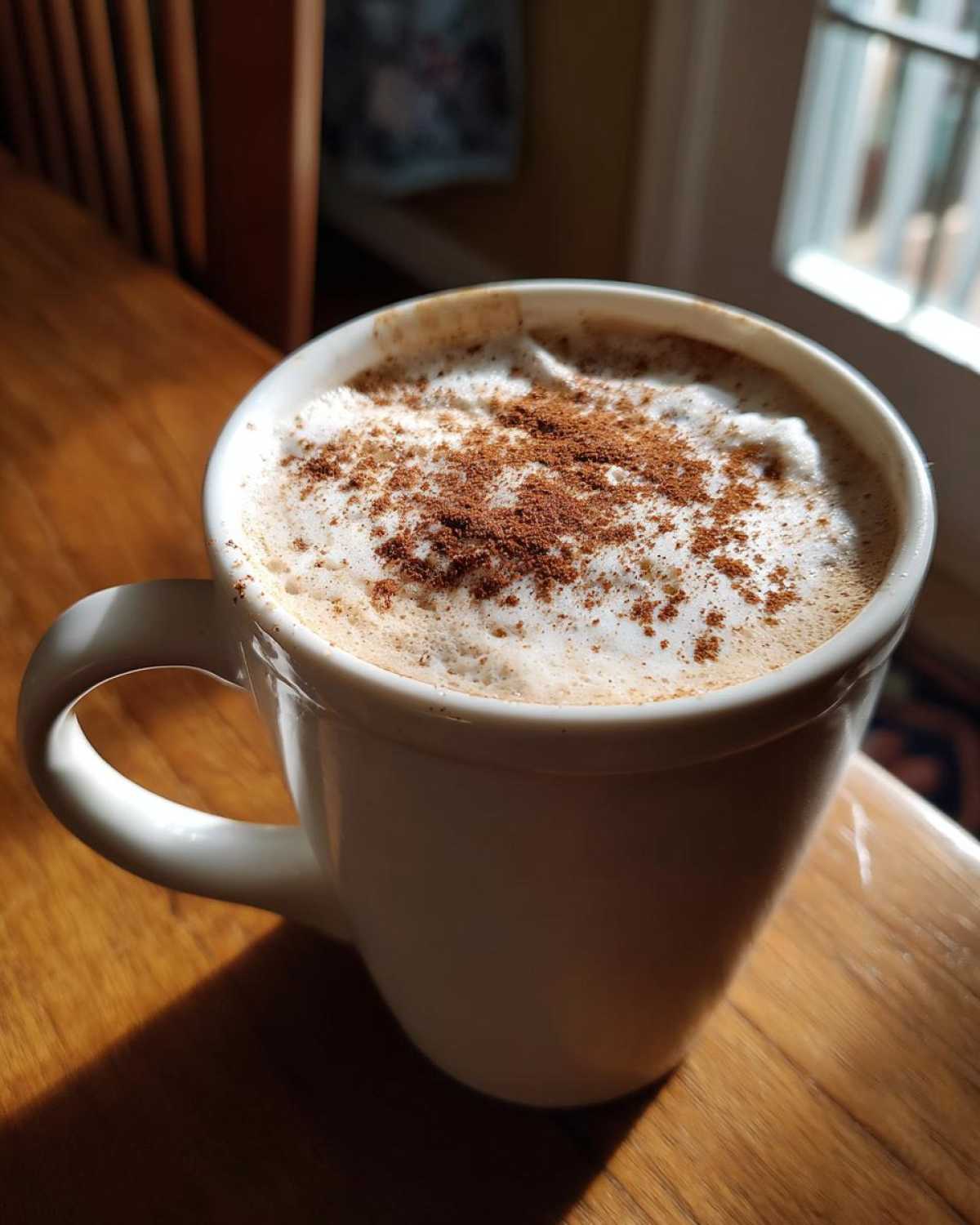 A delicious pumpkin spice latte in a white mug, topped with foam and pumpkin spice.