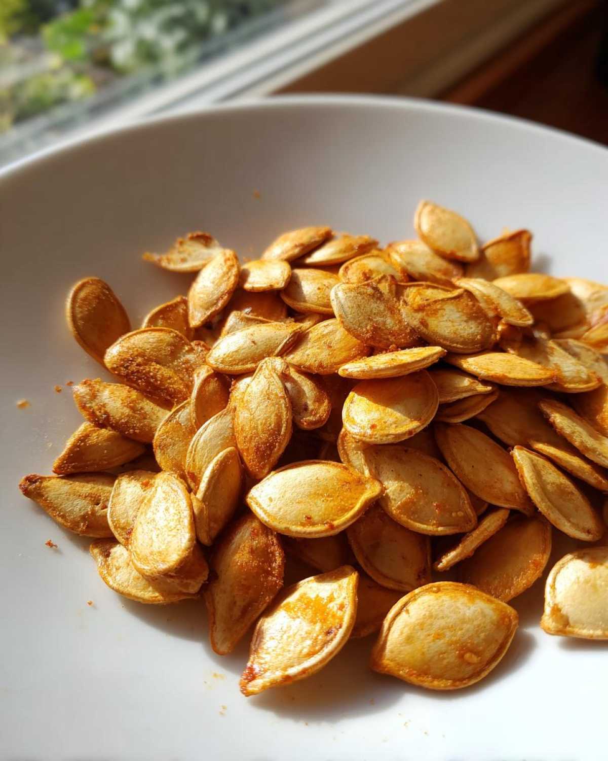 Close-up of a bowl filled with golden brown roasted pumpkin seeds.