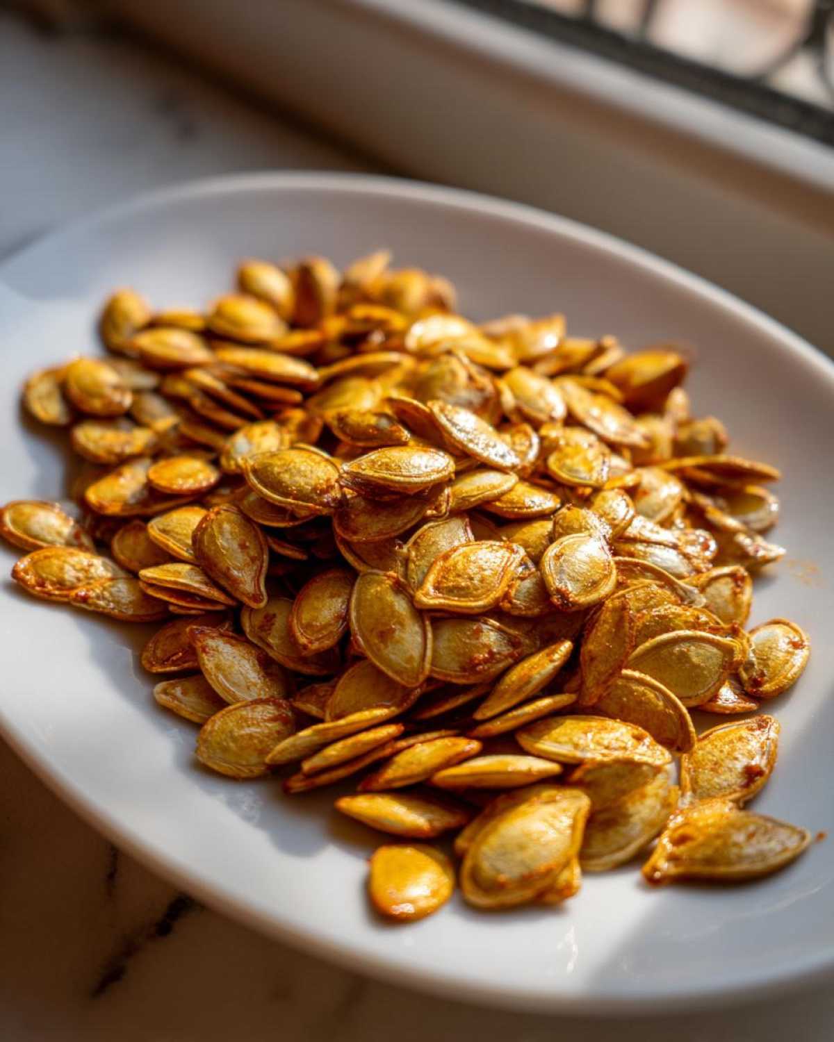 A plate of golden brown roasted pumpkin seeds, showcasing their crispy texture and seasoning.