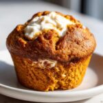 A close-up of a Starbucks pumpkin cream cheese muffin on a white plate.