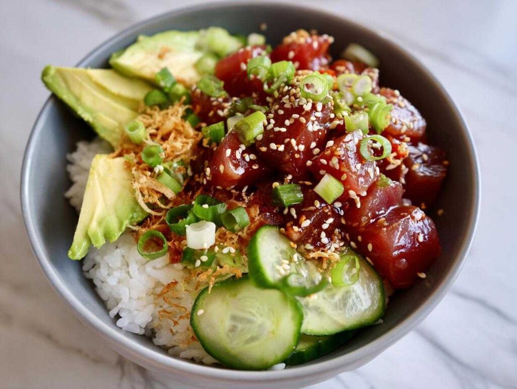 Overhead view of a vibrant tuna poke bowl with rice, avocado, cucumber, and sesame seeds.