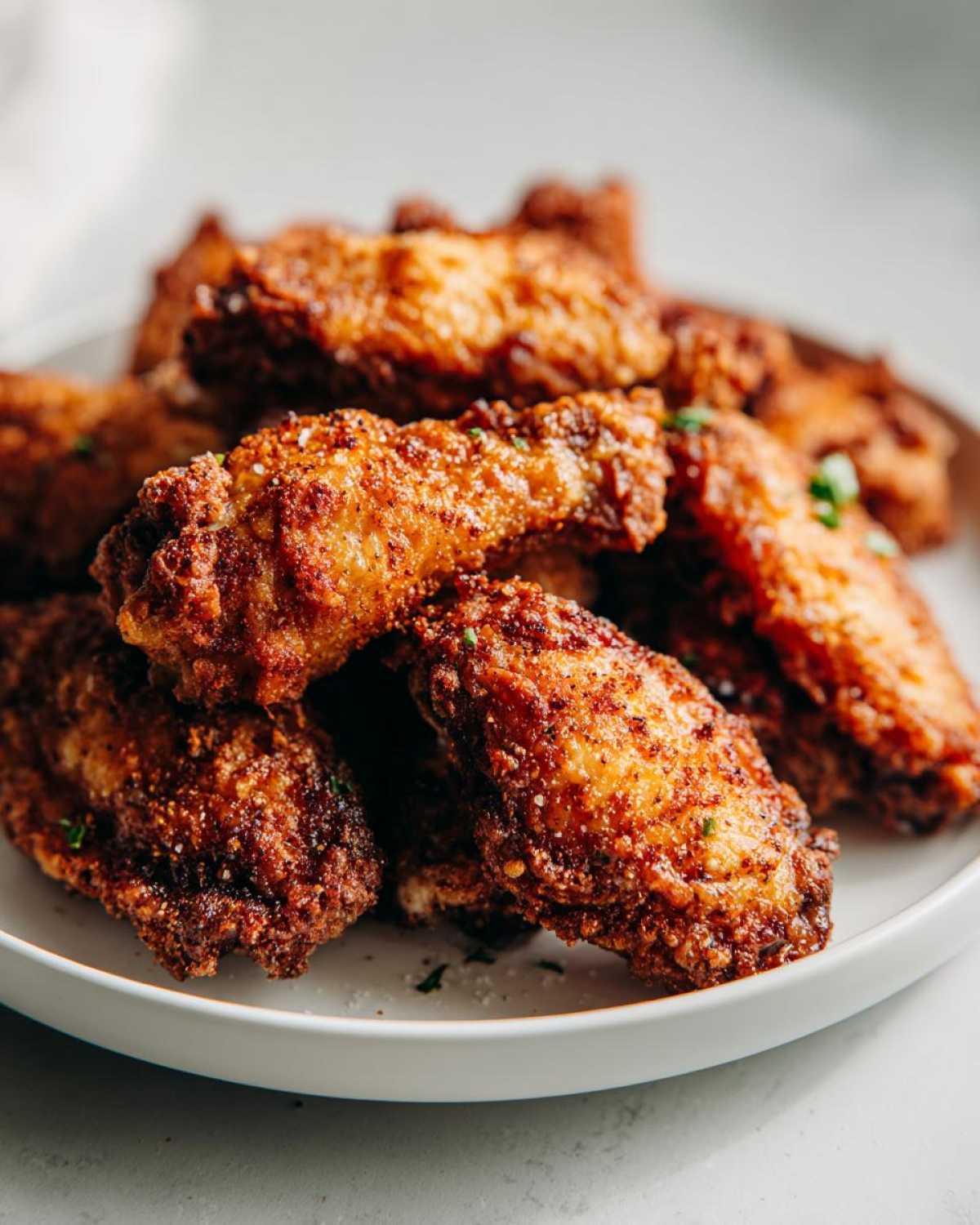 A close-up shot of a pile of crispy air fryer chicken wings seasoned with spices and herbs.