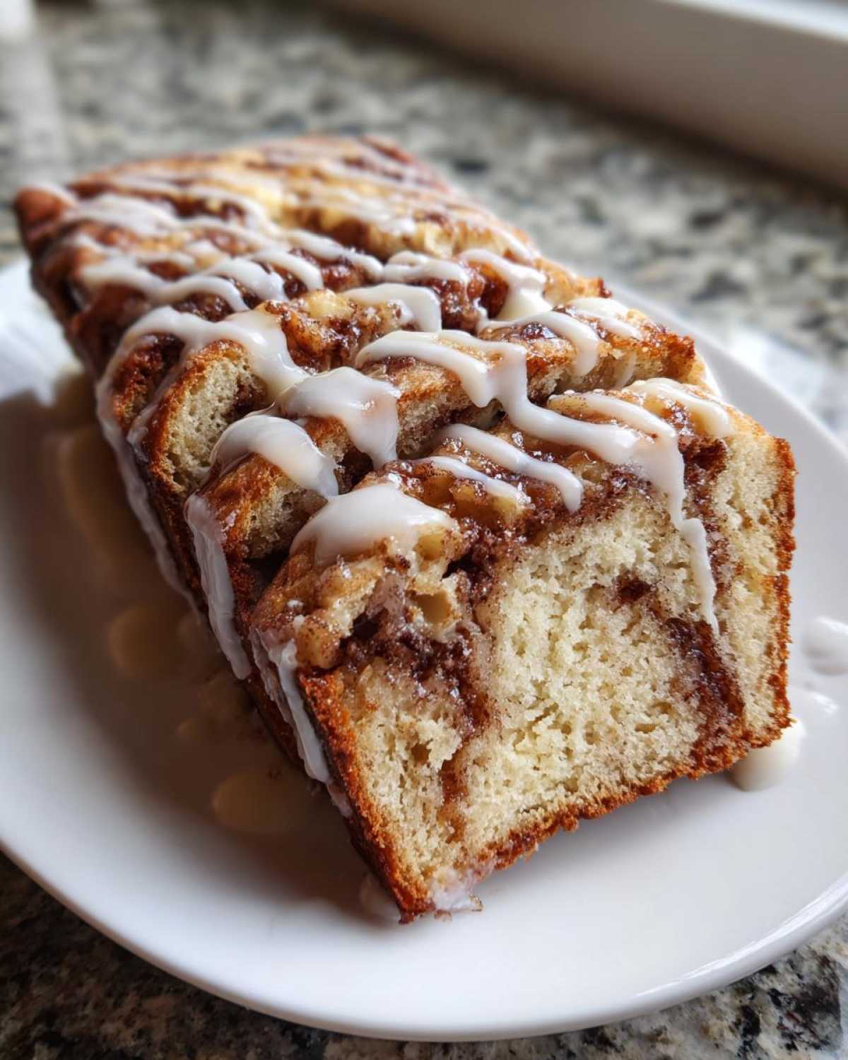 A slice of moist apple fritter bread drizzled with a sweet white glaze.
